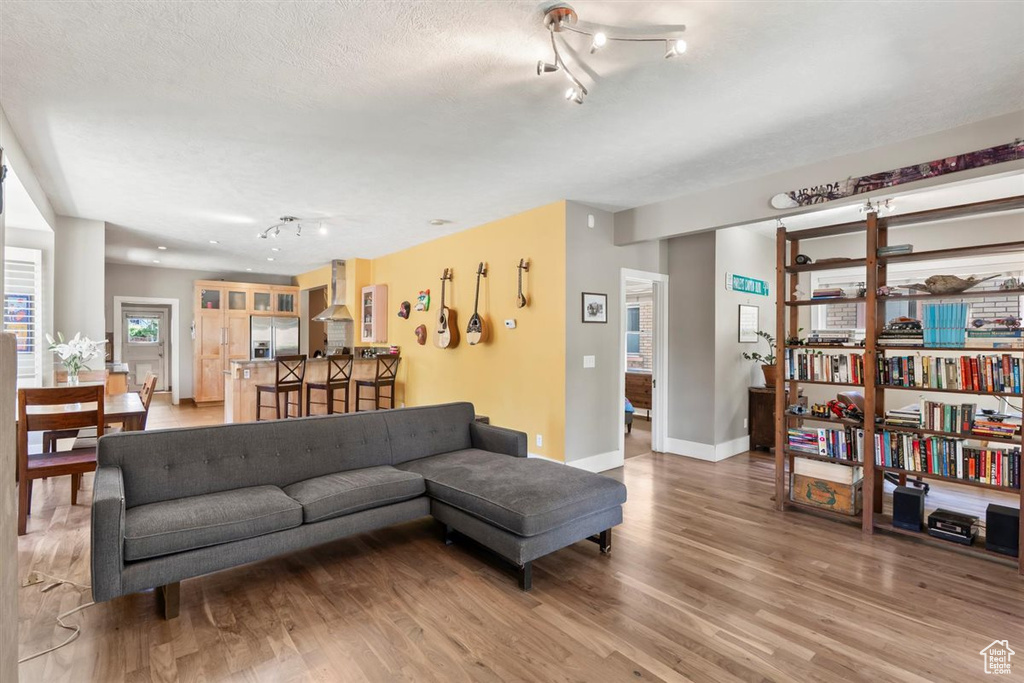 Living area featuring a textured ceiling, baseboards, track lighting, and light wood-style floors