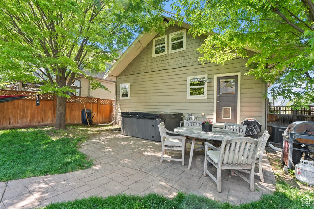 View of patio / terrace featuring a fenced backyard, a hot tub, grilling area, and outdoor dining space
