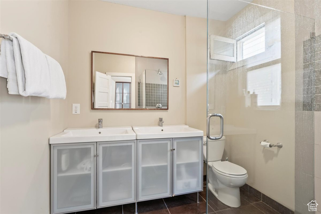 Full bath with a sink, tiled shower, tile patterned flooring, and double vanity