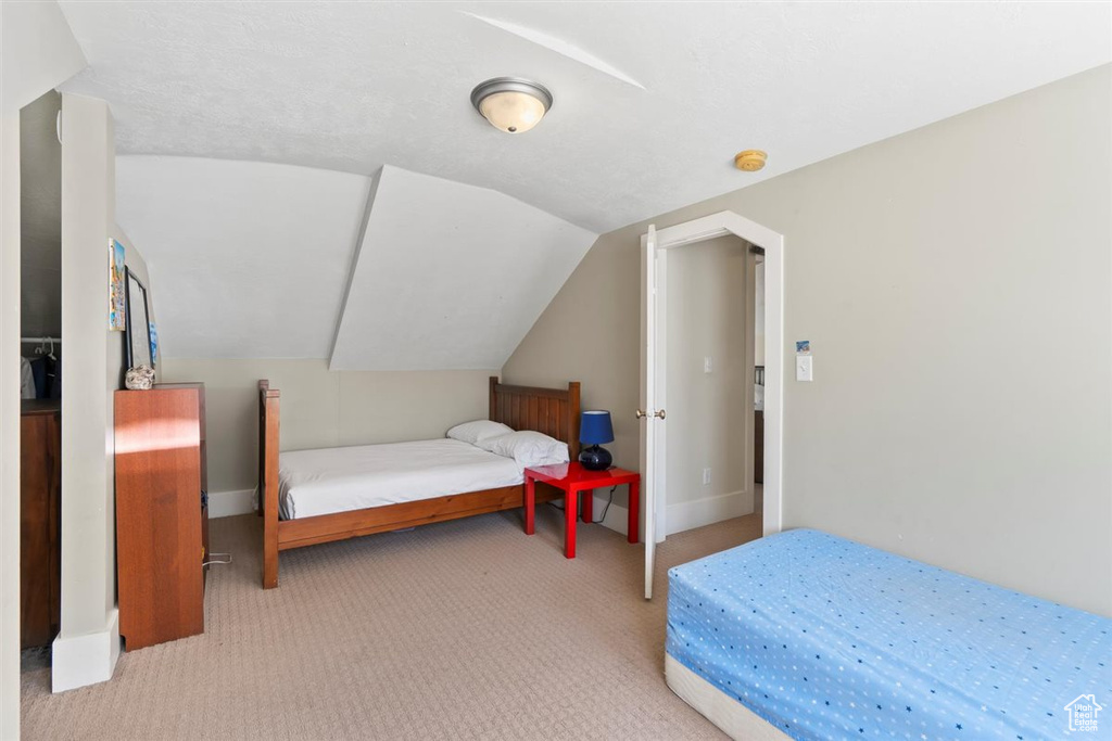 Carpeted bedroom with baseboards and vaulted ceiling
