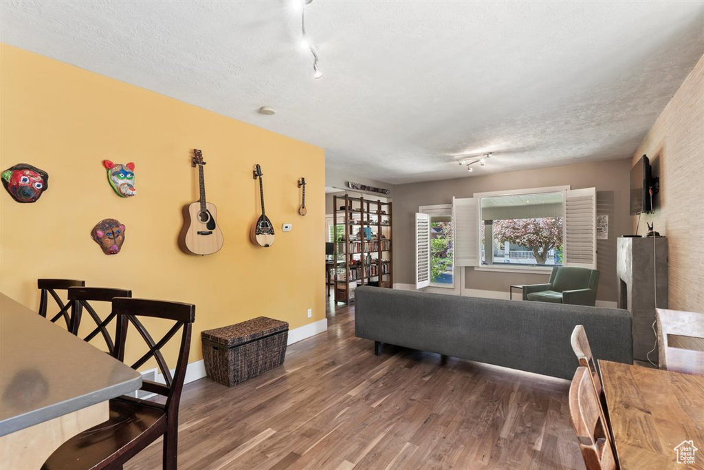 Living area with baseboards, rail lighting, a textured ceiling, and wood finished floors