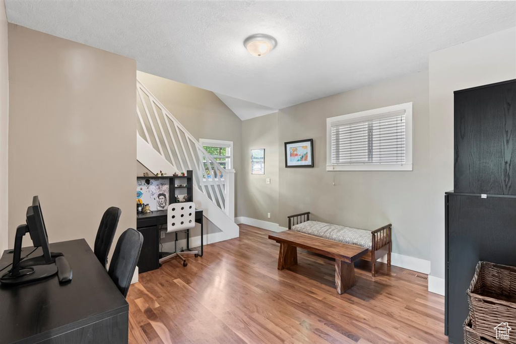 Office area featuring baseboards, light wood-style flooring, and lofted ceiling