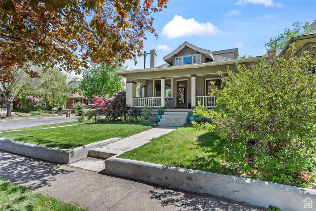 View of front of home with covered porch and a front lawn