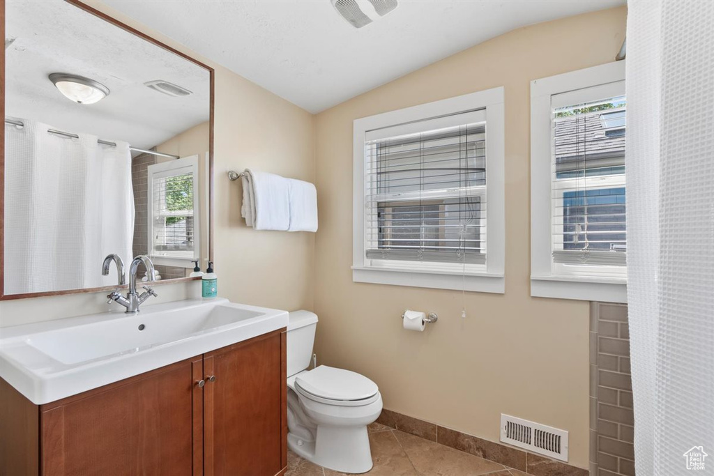 Full bath with toilet, visible vents, plenty of natural light, and vaulted ceiling