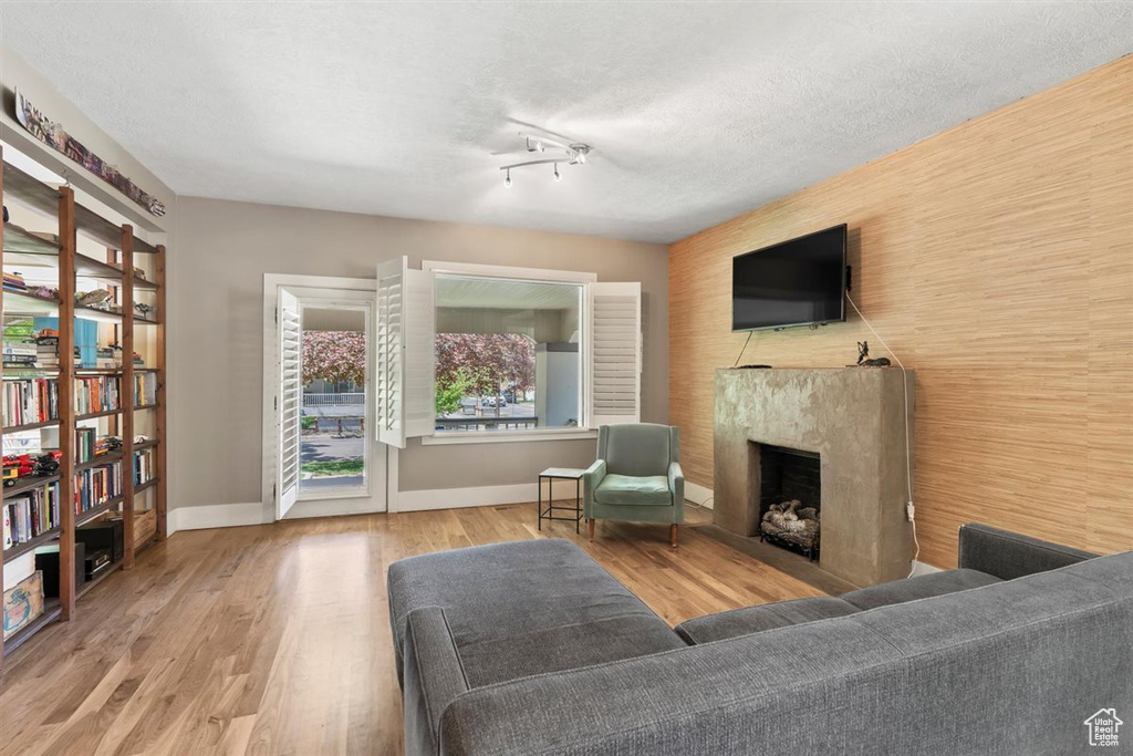 Living area featuring a textured ceiling, baseboards, wood finished floors, and a fireplace