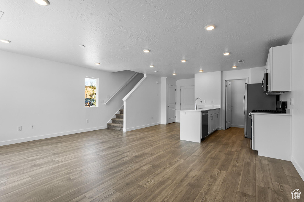 Kitchen featuring dishwashing machine, open floor plan, recessed lighting, and wood finished floors