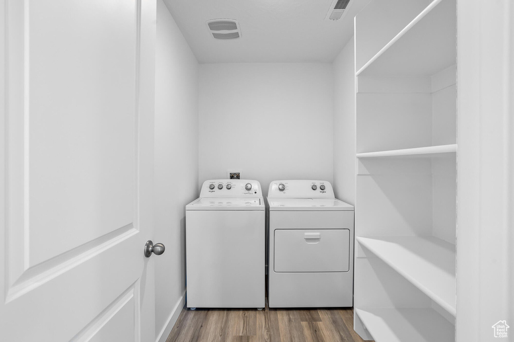 Clothes washing area with laundry area, visible vents, independent washer and dryer, and dark wood finished floors