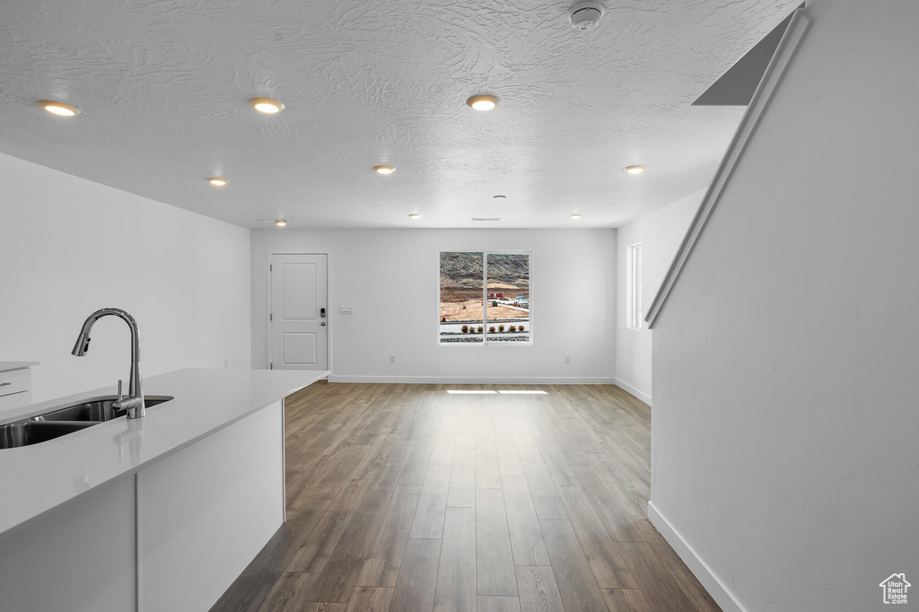 Unfurnished living room with baseboards, dark wood finished floors, and a sink