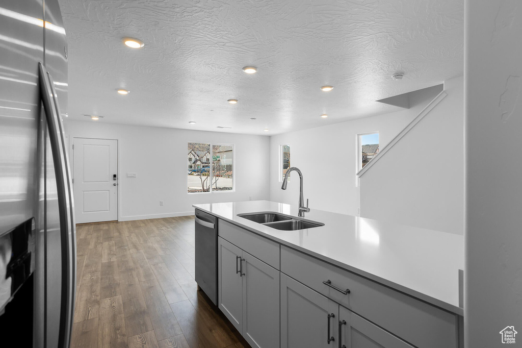 Kitchen with baseboards, dark wood-style flooring, a sink, light countertops, and appliances with stainless steel finishes
