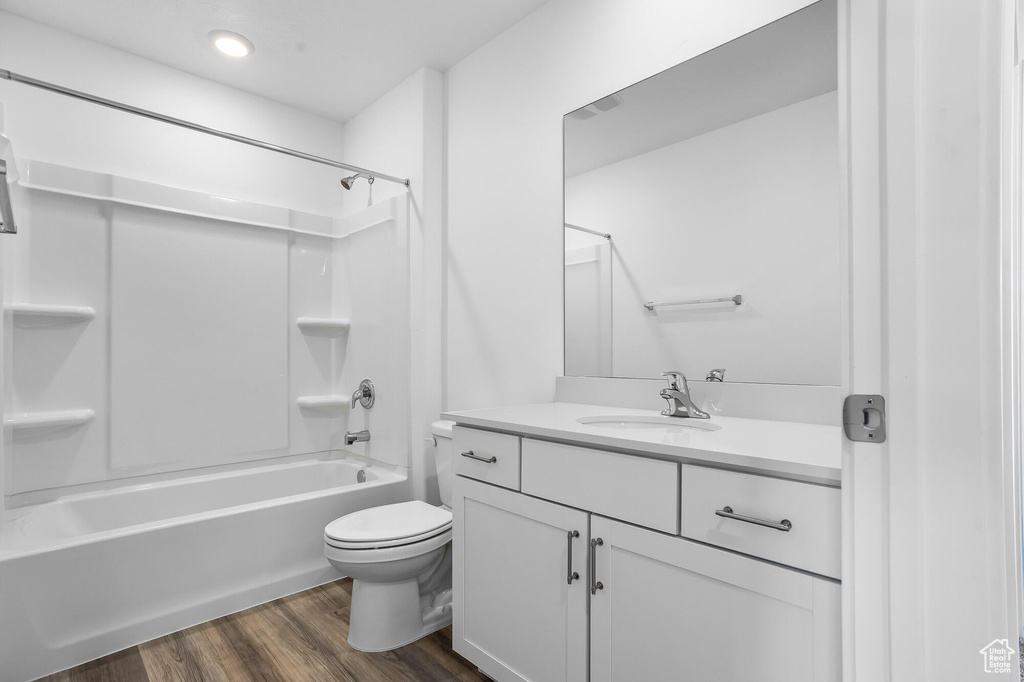 Bathroom featuring vanity, toilet, shower / tub combination, and wood finished floors