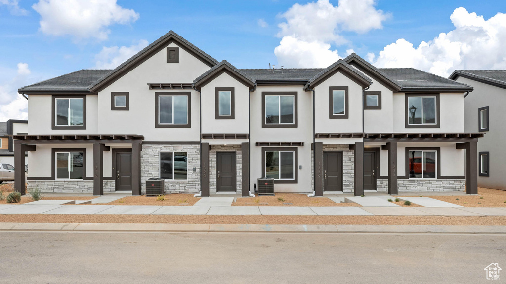 Townhome / multi-family property featuring stucco siding, cooling unit, and stone siding
