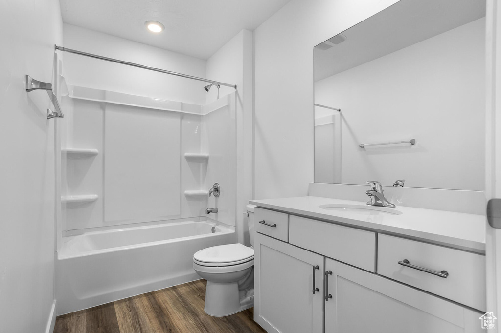 Bathroom with vanity, toilet, bathtub / shower combination, and wood finished floors