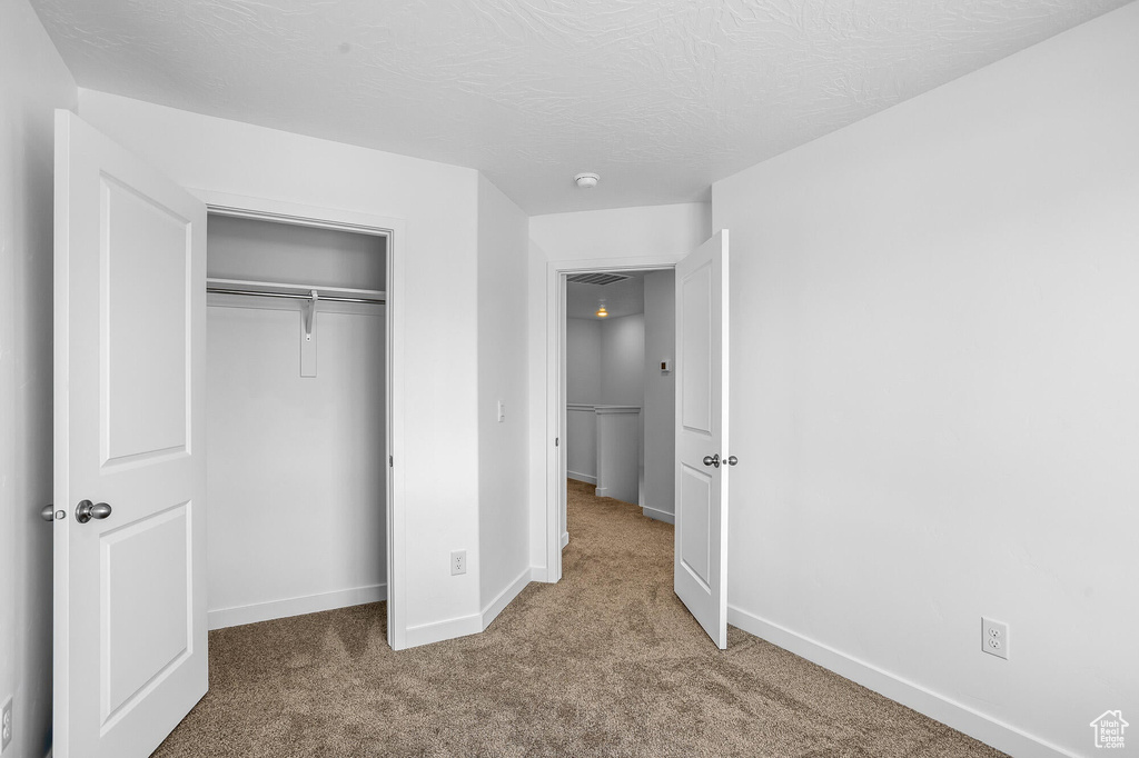 Unfurnished bedroom featuring baseboards, a closet, and carpet floors