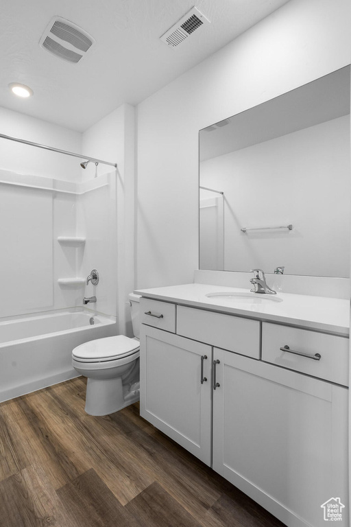 Bathroom with toilet, visible vents, wood finished floors, and vanity