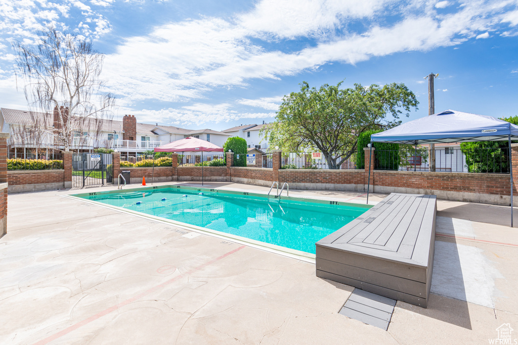 Community pool featuring fence, a residential view, and a patio area