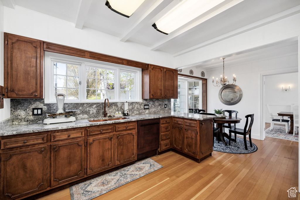 Kitchen featuring a sink, tasteful backsplash, beam ceiling, dishwasher, and light wood finished floors