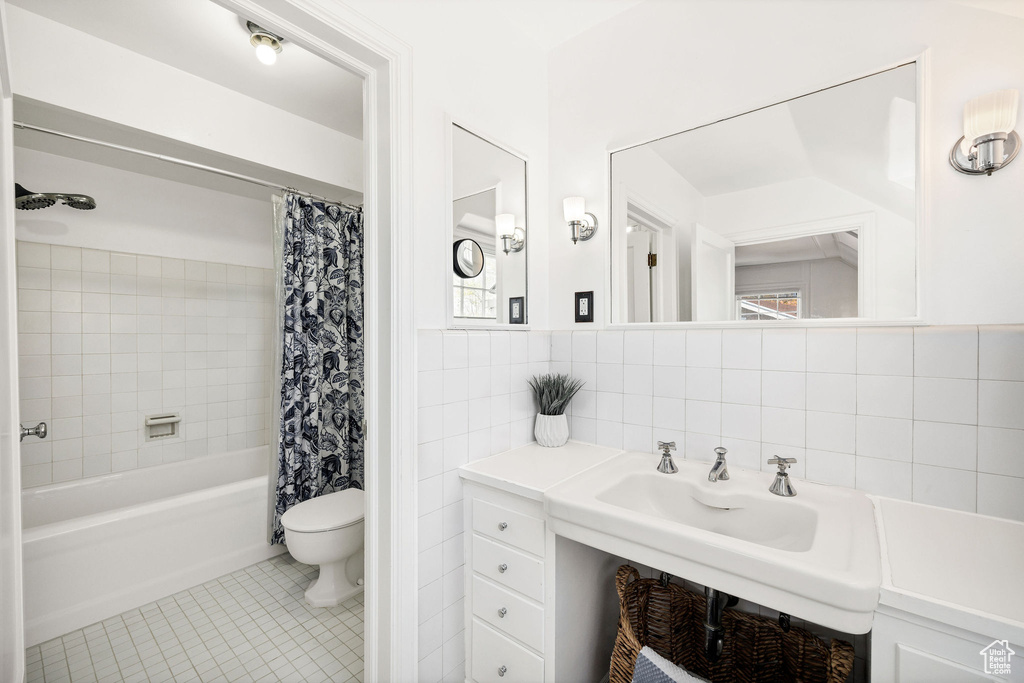 Full bathroom featuring toilet, tile walls, tile patterned floors, and shower / tub combo