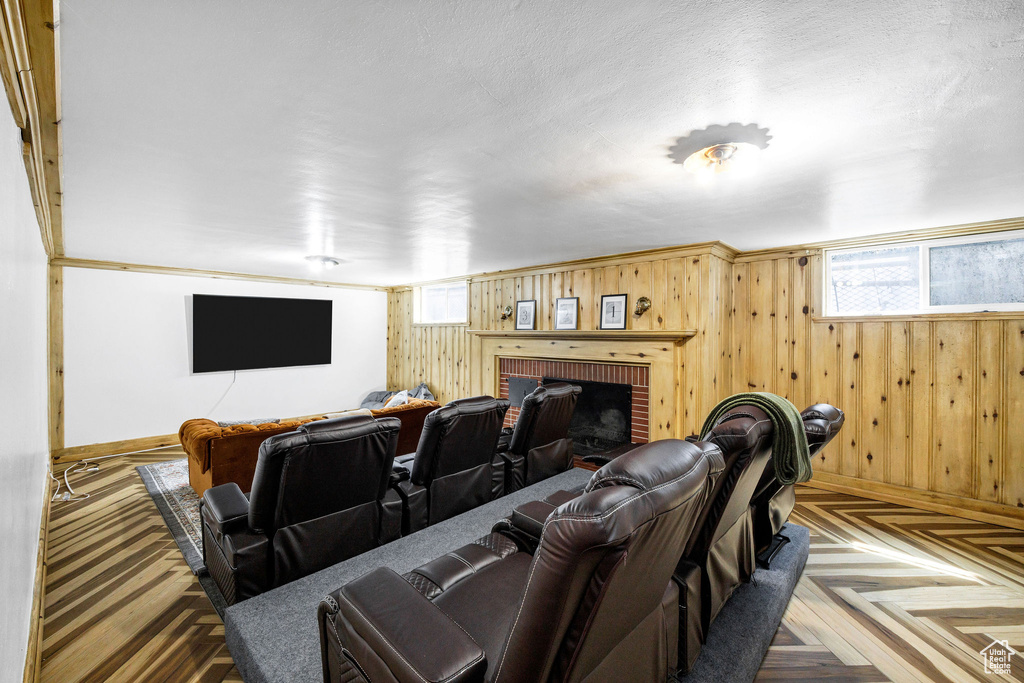 Home theater room with baseboards, wood walls, and a fireplace