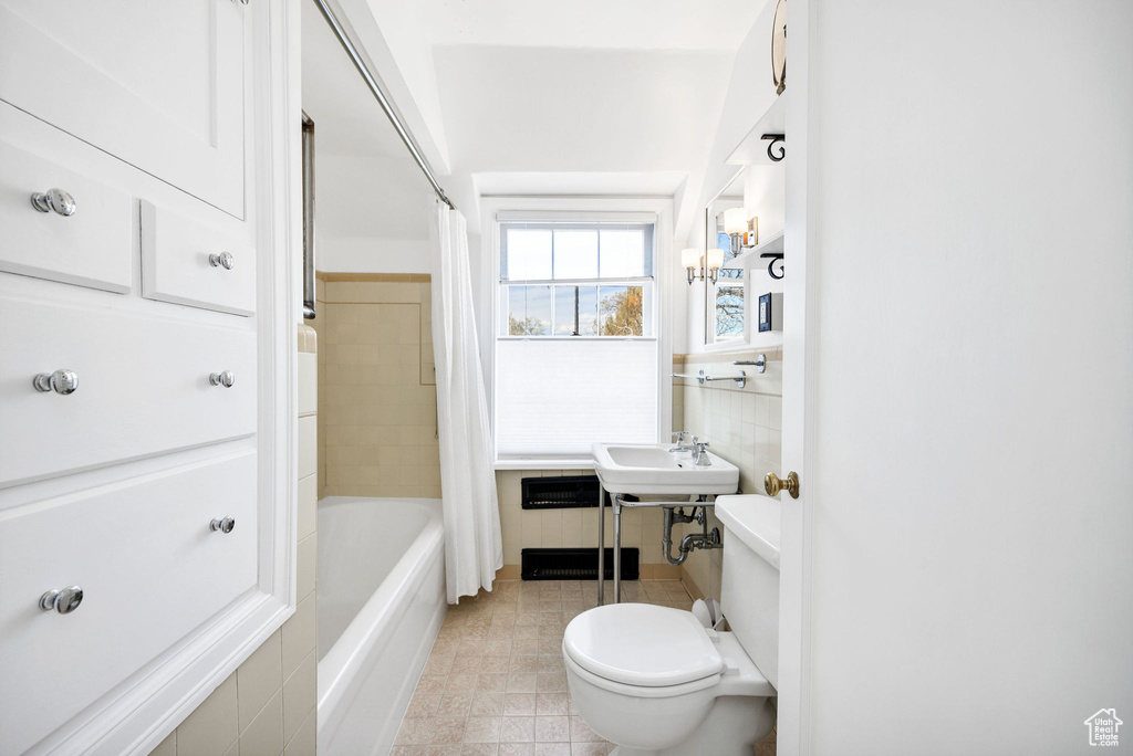 Full bath featuring tile walls, toilet, shower / tub combo with curtain, a sink, and tile patterned flooring