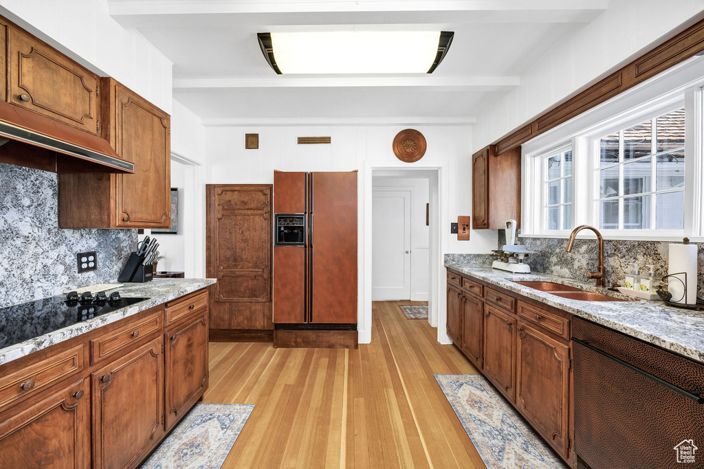 Kitchen with light wood-style flooring, dishwasher, refrigerator with ice dispenser, a sink, and tasteful backsplash