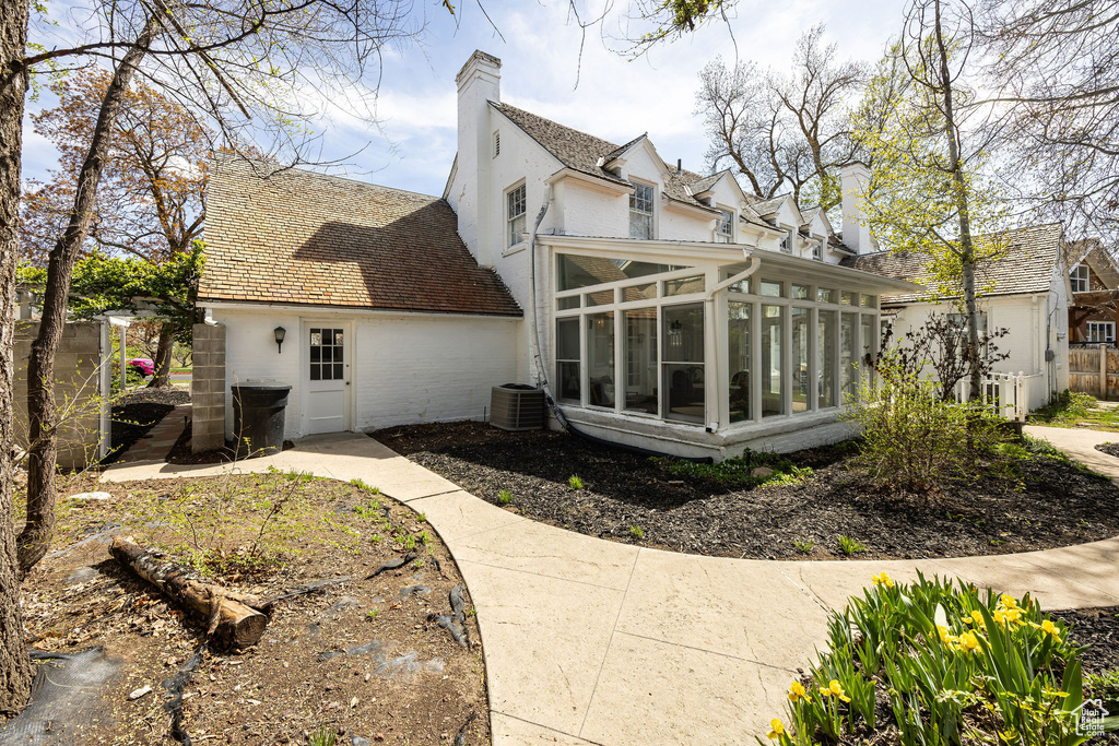 View of home\'s exterior featuring a chimney, central air condition unit, and a sunroom