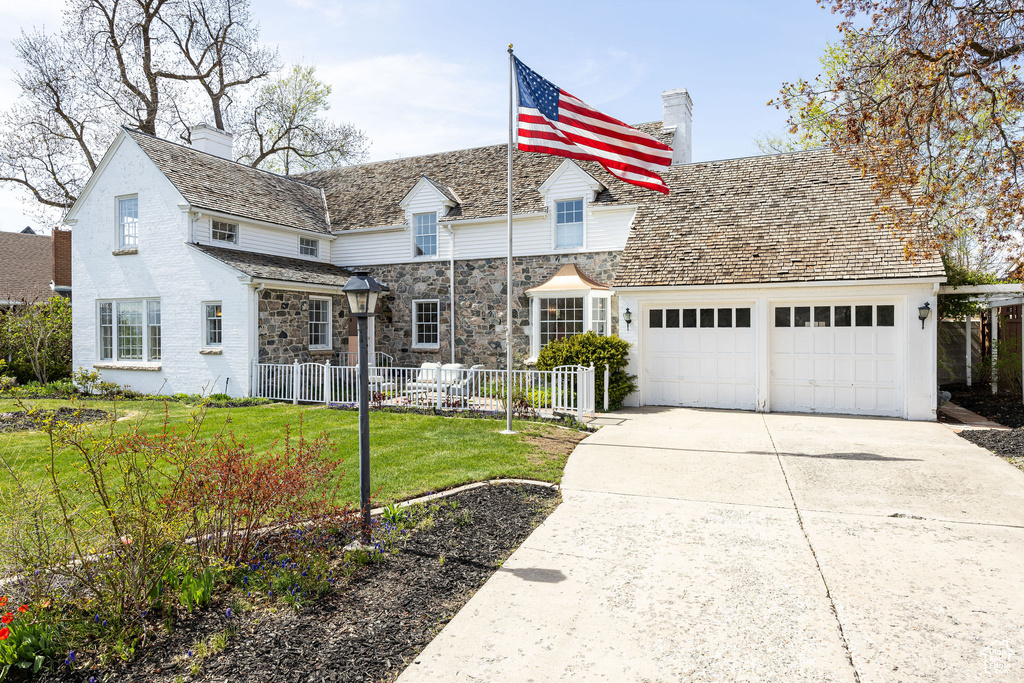 View of front of home with fence, concrete driveway, a garage, a front yard, and a chimney