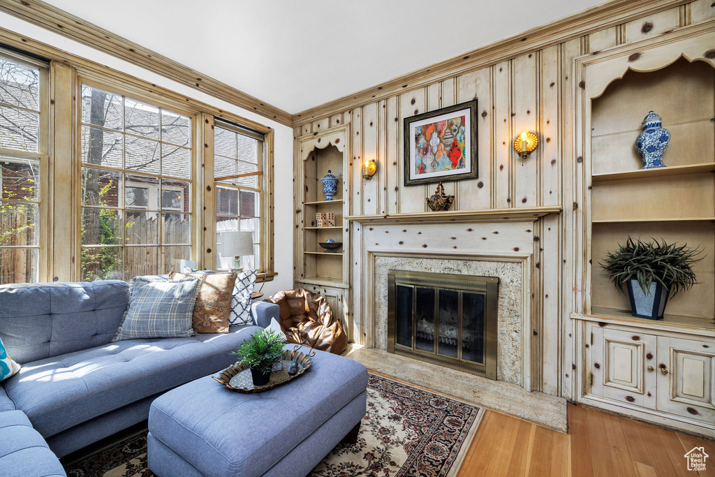 Living room with a premium fireplace, built in features, wood finished floors, and a healthy amount of sunlight