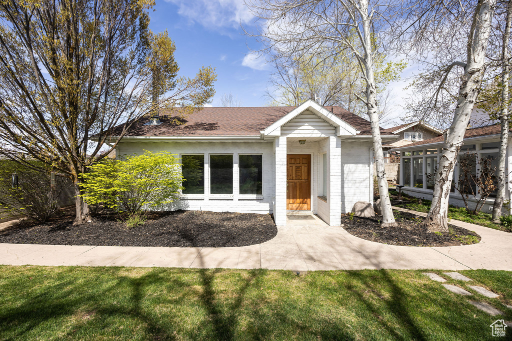 View of front of home featuring a front lawn, a shingled roof, and brick siding