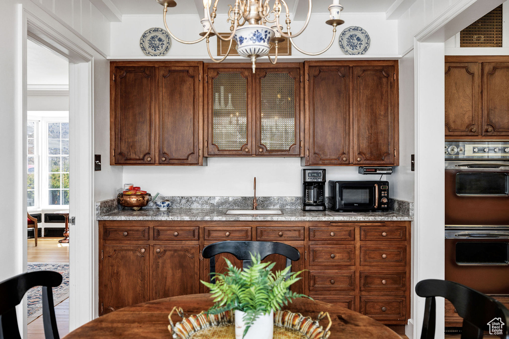 Bar featuring double wall oven, a sink, a notable chandelier, visible vents, and black microwave