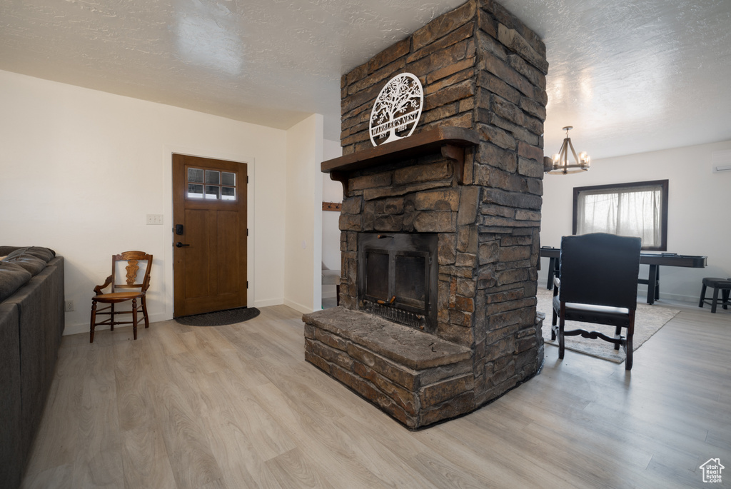 Living room with a textured ceiling, wood finished floors, a fireplace, a chandelier, and baseboards