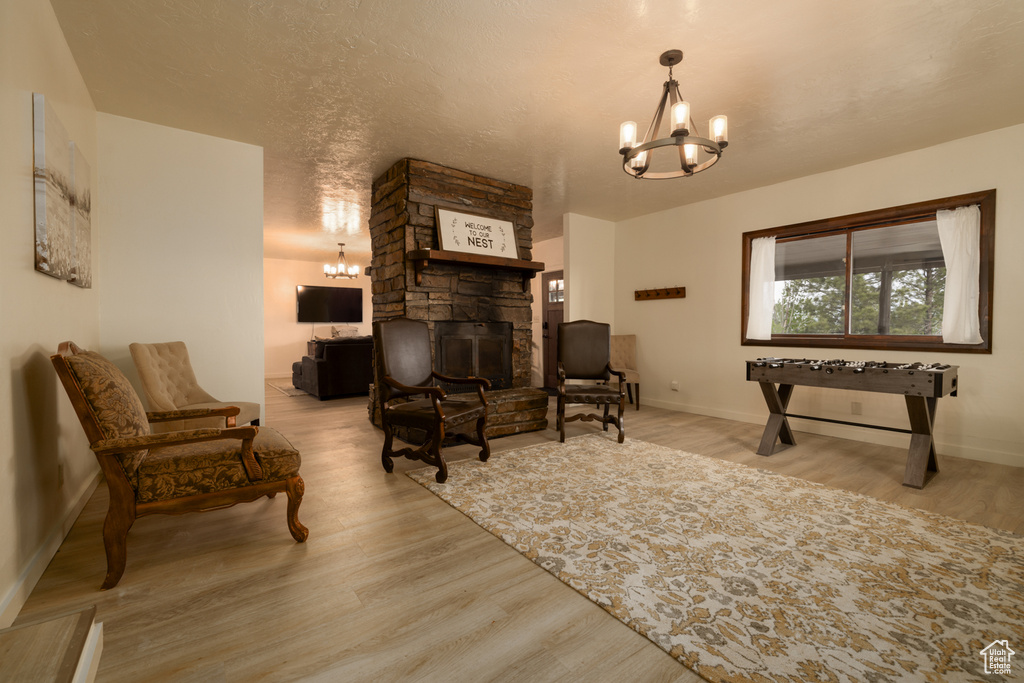 Sitting room featuring a chandelier, a stone fireplace, wood finished floors, and baseboards