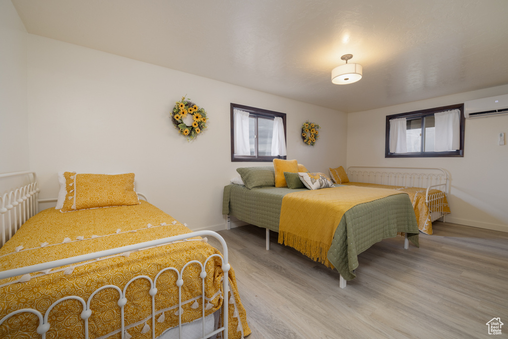 Bedroom featuring a wall unit AC, wood finished floors, and baseboards