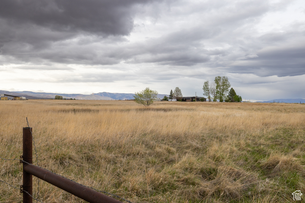 View of yard featuring a rural view, a mountain view, and fence
