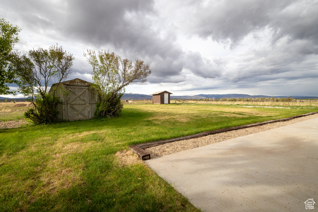 View of green lawn featuring an outdoor structure and a storage shed