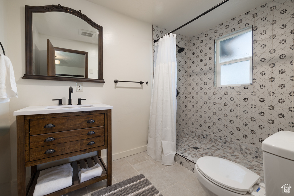 Full bathroom featuring toilet, a stall shower, vanity, and baseboards