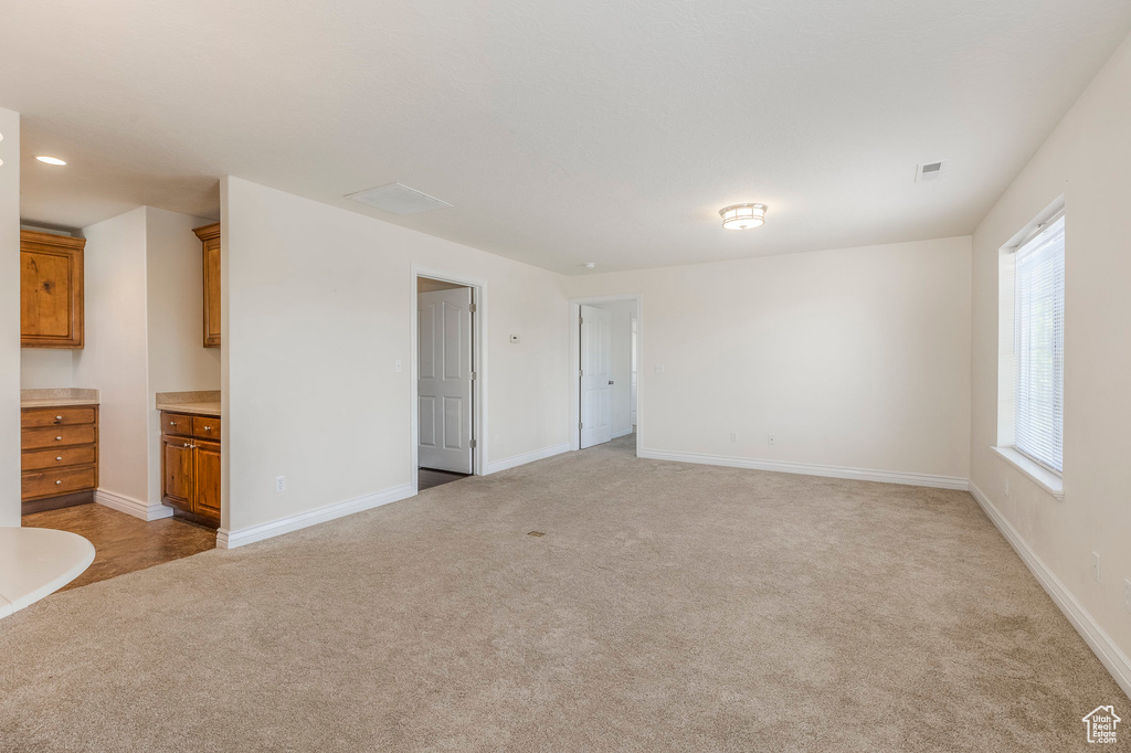 Unfurnished living room featuring light colored carpet, visible vents, and baseboards