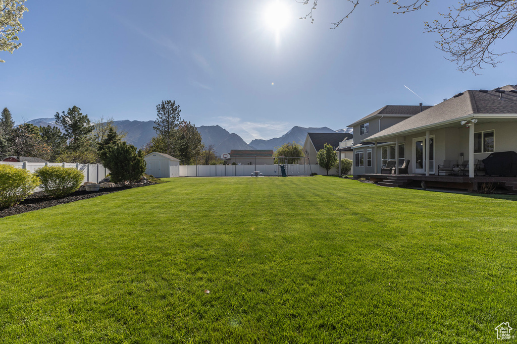 View of yard with a storage shed, a mountain view, an outdoor structure, and a fenced backyard