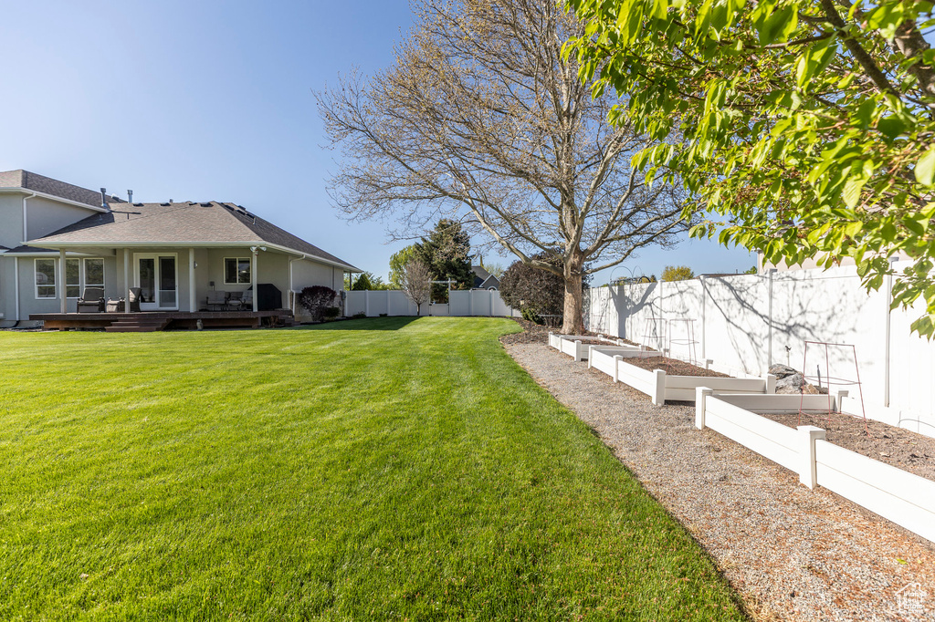 View of yard featuring a vegetable garden, a wooden deck, and a fenced backyard