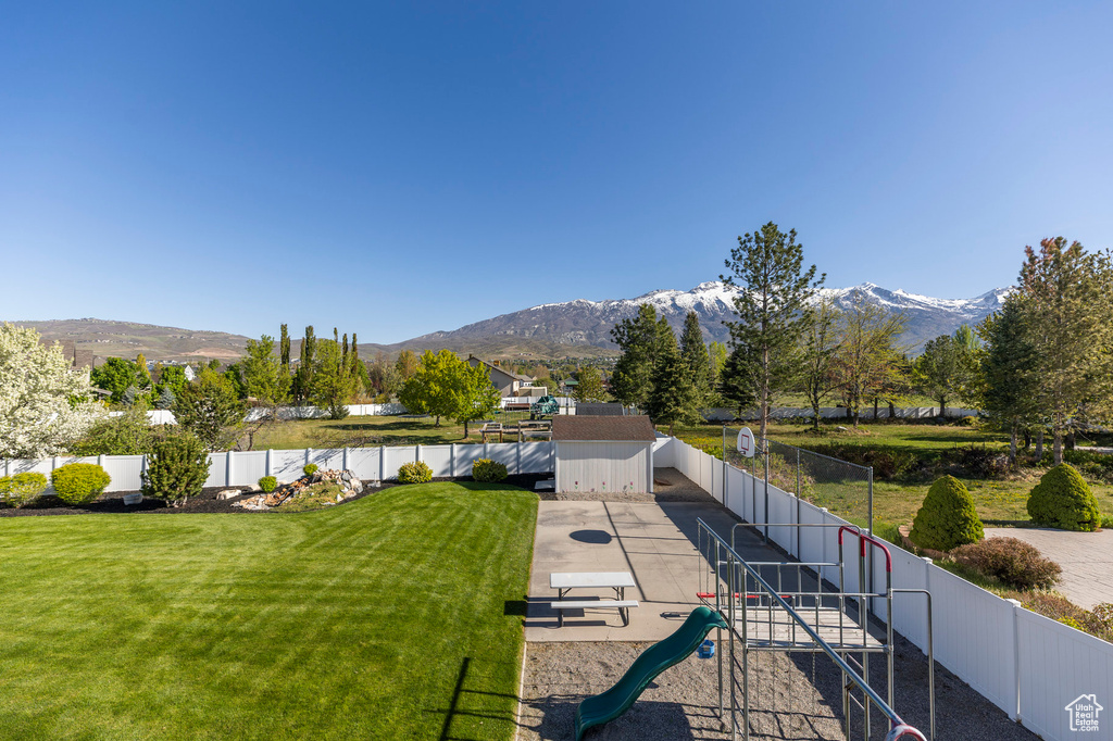 View of property\'s community with playground community, a mountain view, and a fenced backyard