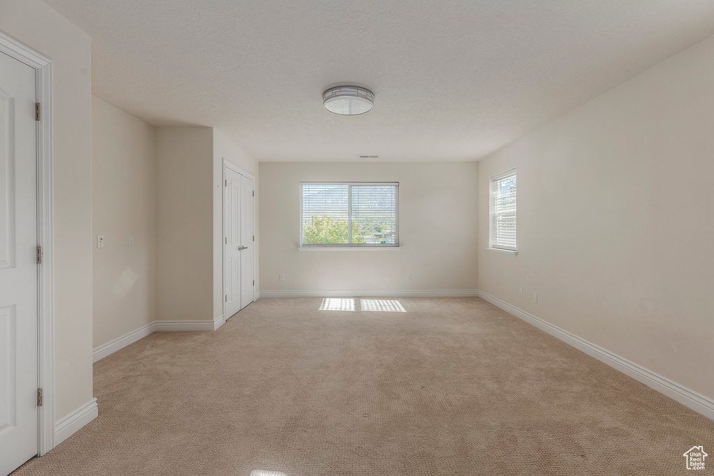 Empty room with baseboards and light colored carpet