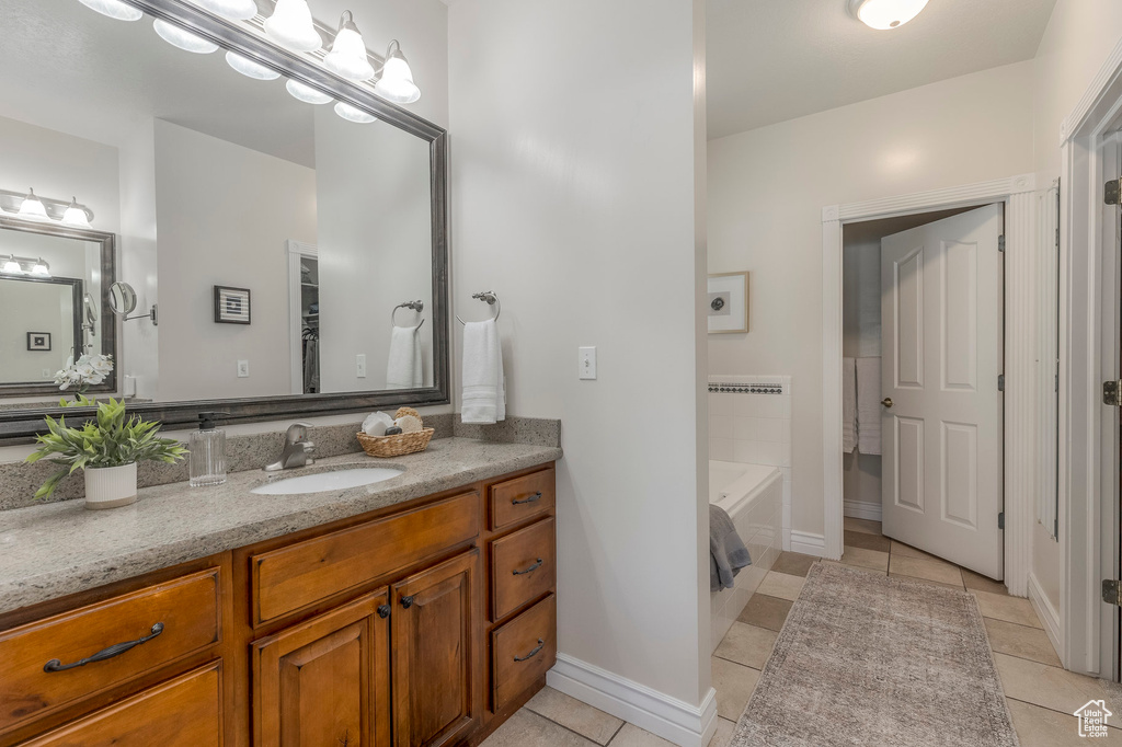 Bathroom featuring vanity, a tub to relax in, baseboards, and tile patterned floors