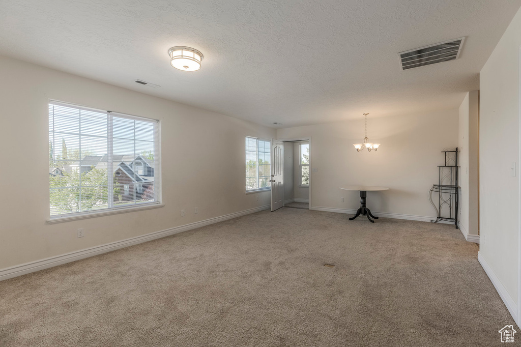 Empty room with baseboards, light carpet, a chandelier, and visible vents