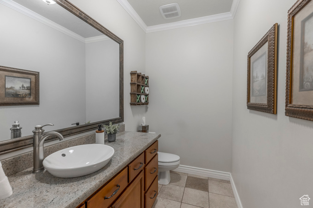 Bathroom with toilet, visible vents, baseboards, vanity, and ornamental molding