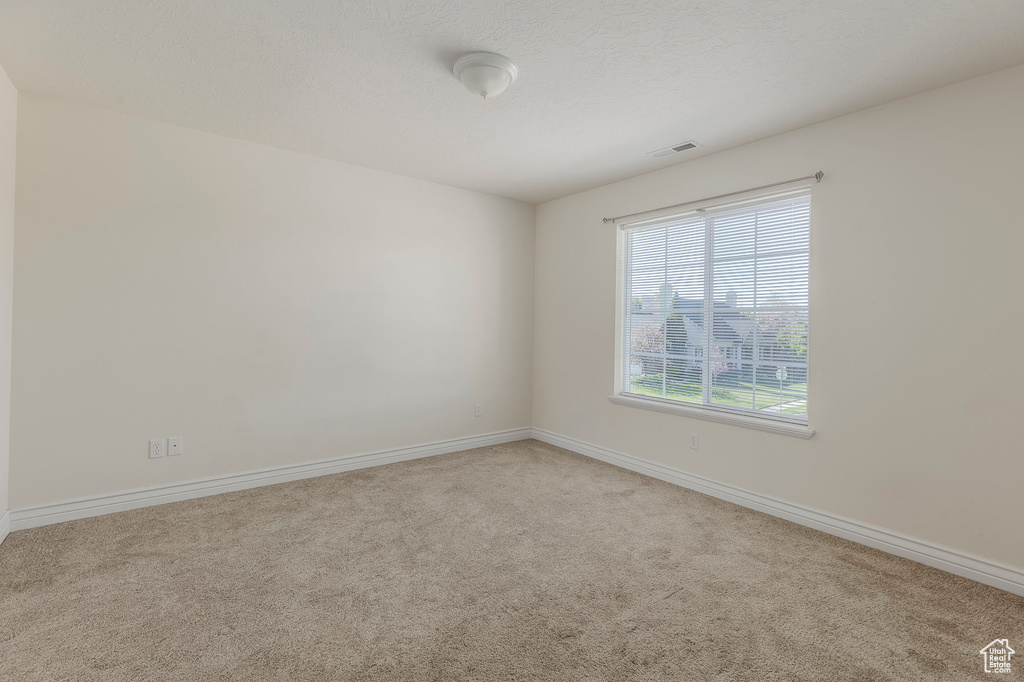 Carpeted empty room featuring visible vents and baseboards