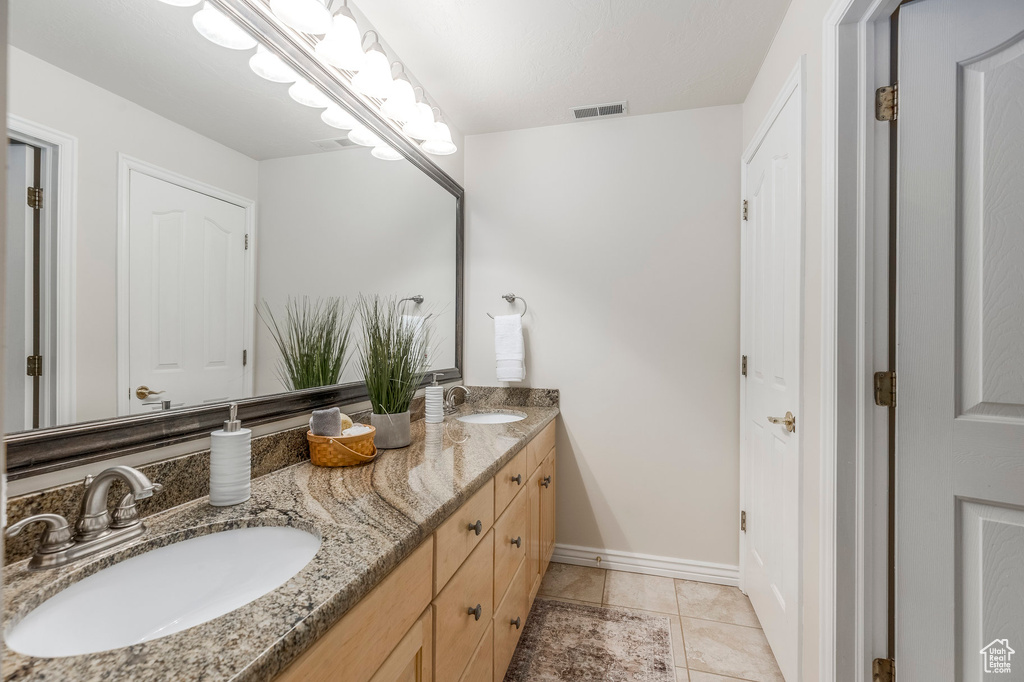 Bathroom with tile patterned floors, double vanity, visible vents, and a sink