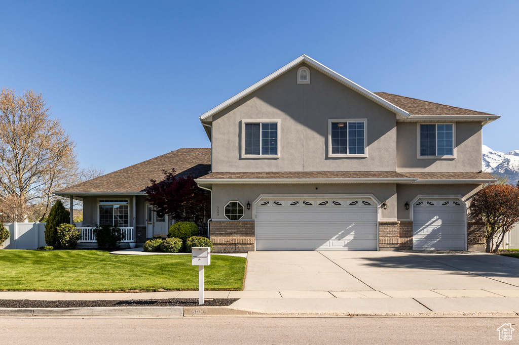 Traditional-style house featuring brick siding, concrete driveway, a garage, stucco siding, and a front lawn