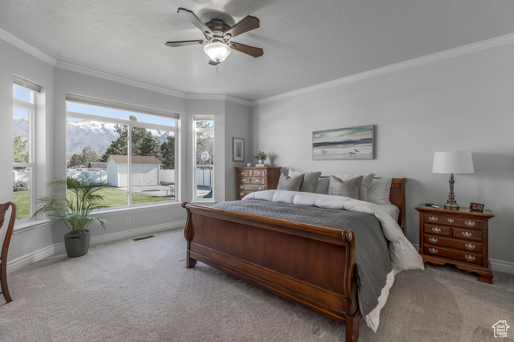 Carpeted bedroom with ornamental molding, a textured ceiling, baseboards, and visible vents