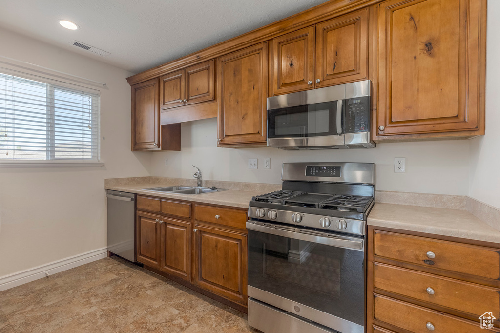 Kitchen featuring stainless steel appliances, brown cabinetry, and visible vents