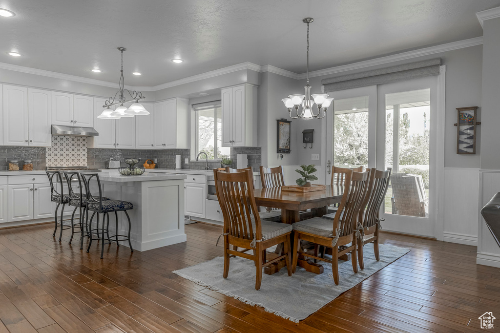 Dining room featuring a wainscoted wall, dark wood-type flooring, a chandelier, ornamental molding, and recessed lighting