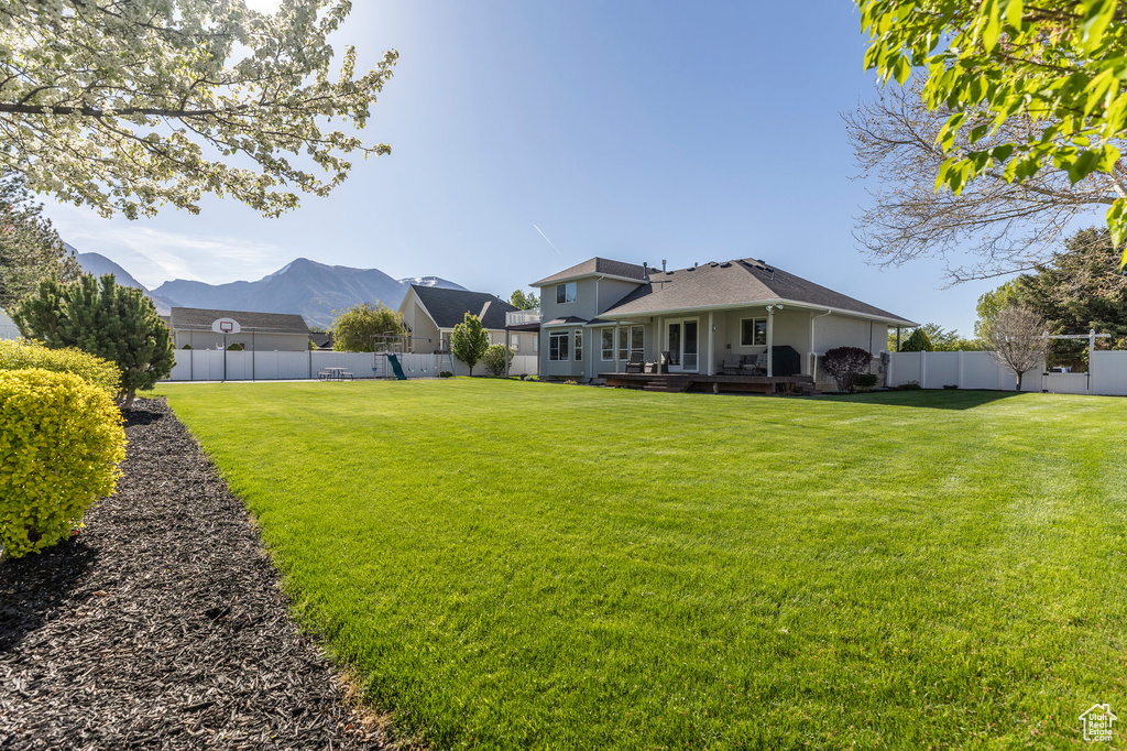 View of yard featuring a deck with mountain view and a fenced backyard
